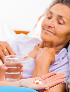 caregiver giving medicines to an elderly woman